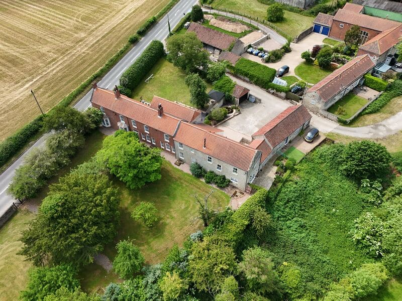 Aerial listing photo showing the property, gardens, outbuildings and surrounding village setting.