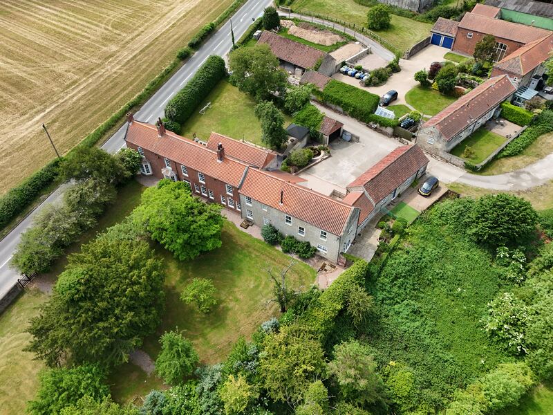 Aerial listing photo showing the property, gardens, outbuildings and surrounding village setting.